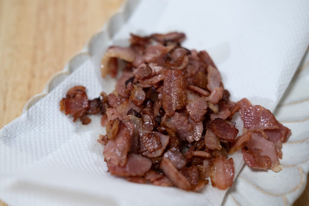 Crispy cooked bite-sized bacon pieces on a plate lined with paper towels.  