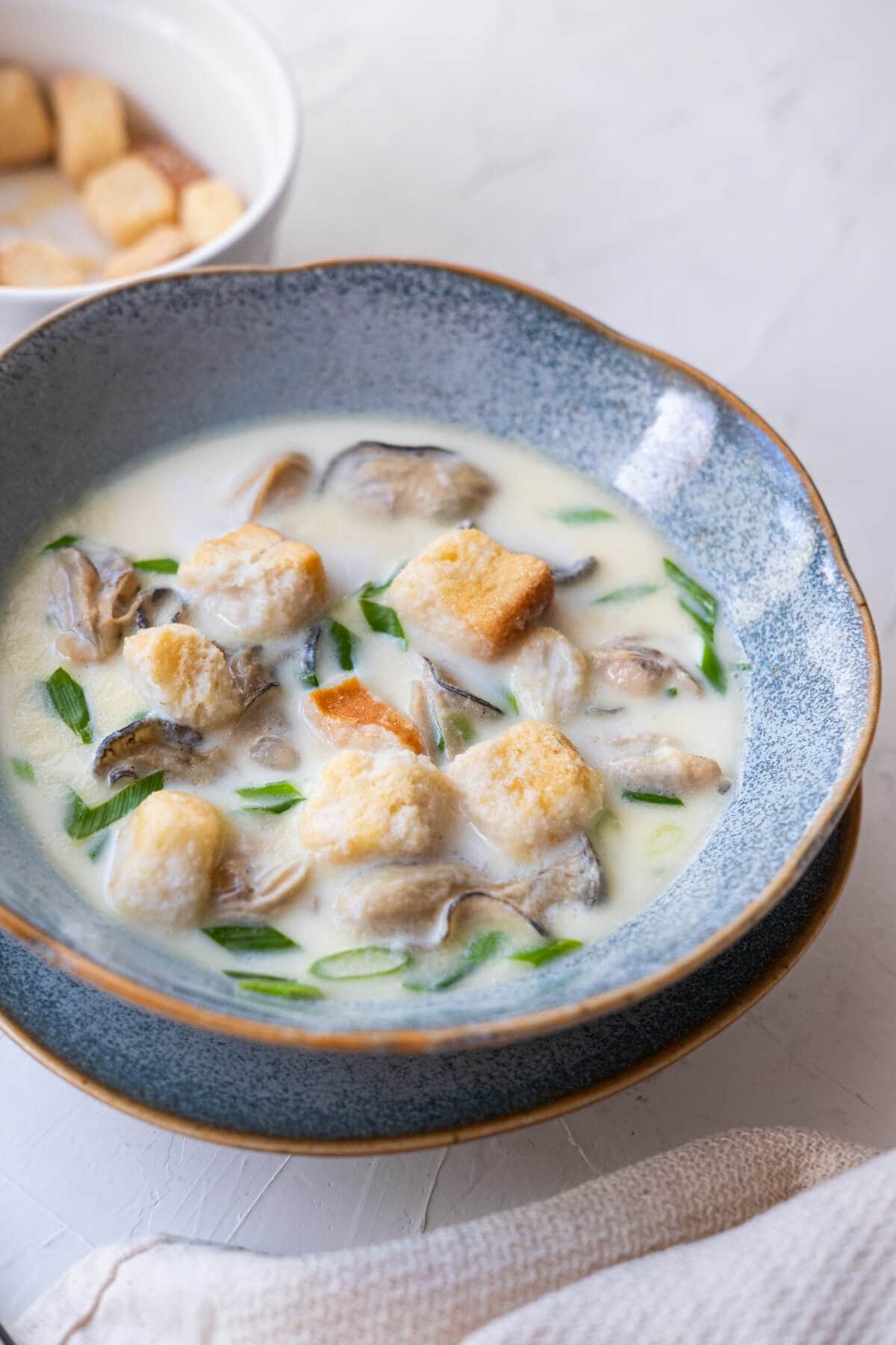 A bowl of stew filled with juicy oysters and served along with croutons. 